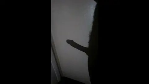 Big Black Cock Casts Shadow on Wall in Dark Room